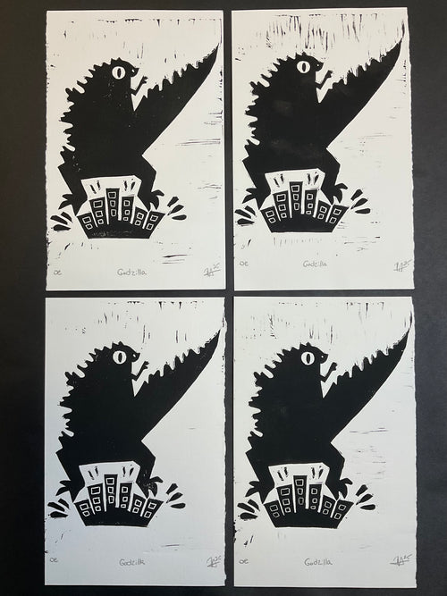 Four black and white linoblock prints on a dark surface.