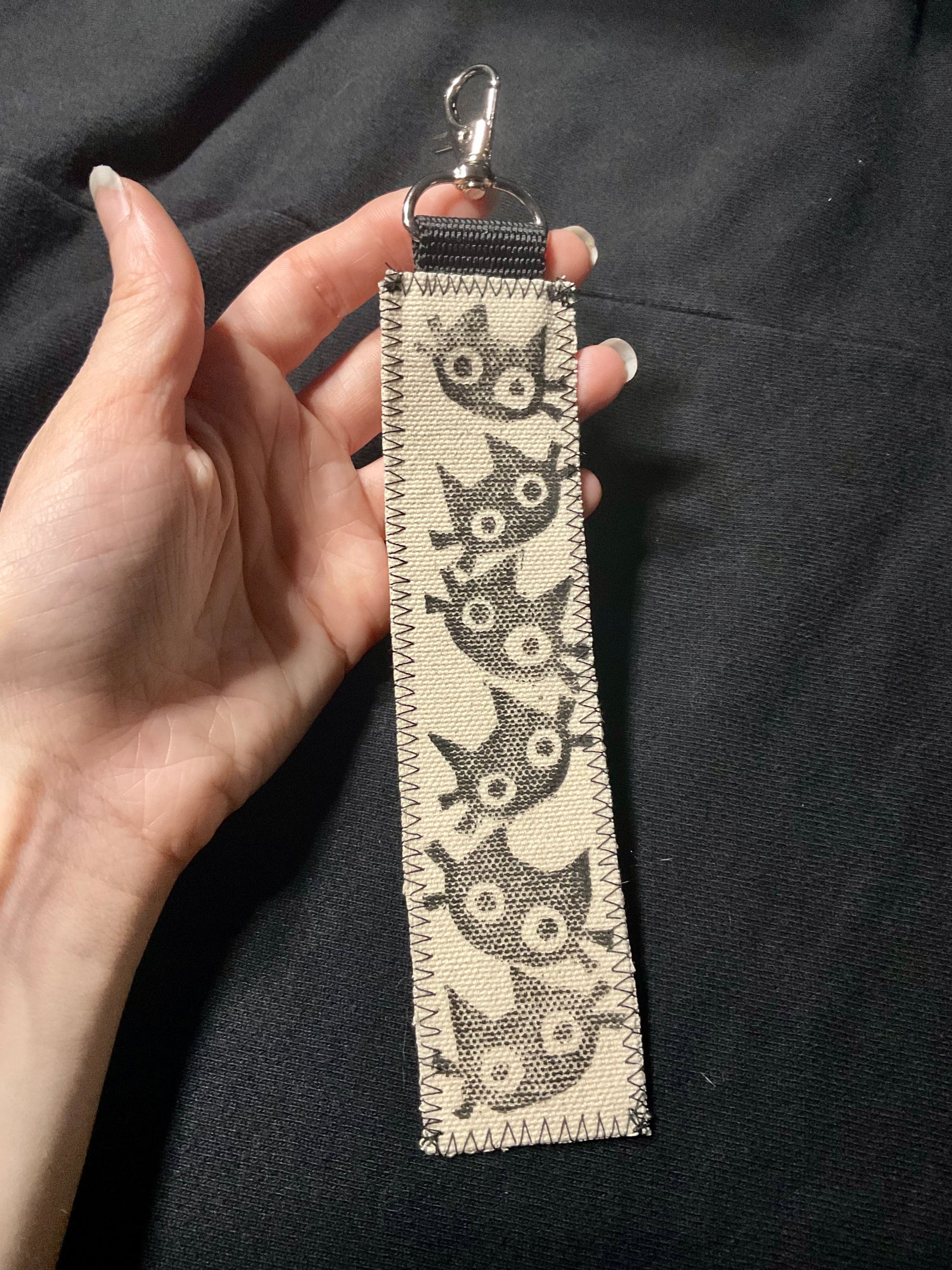 Tan fabric keychain of 6 cats stacked on top of each other.