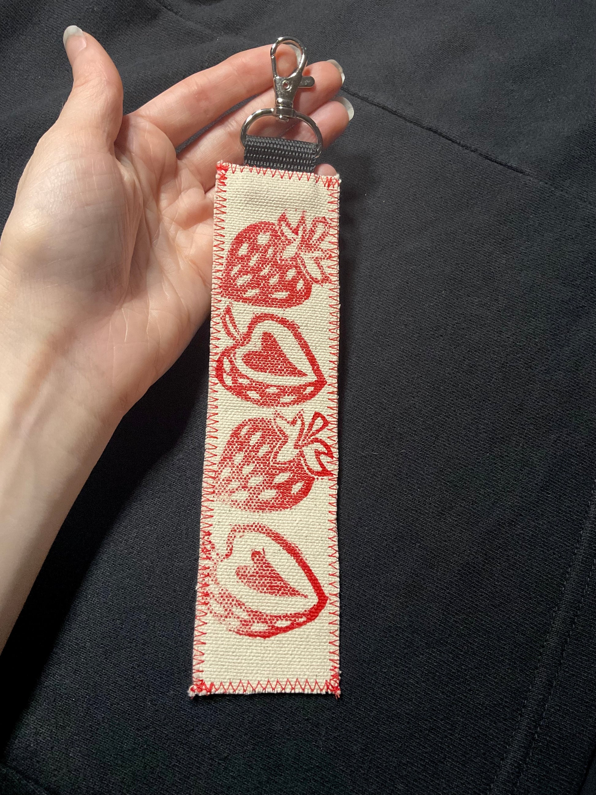 Hand holding a fabric keychain of strawberries.