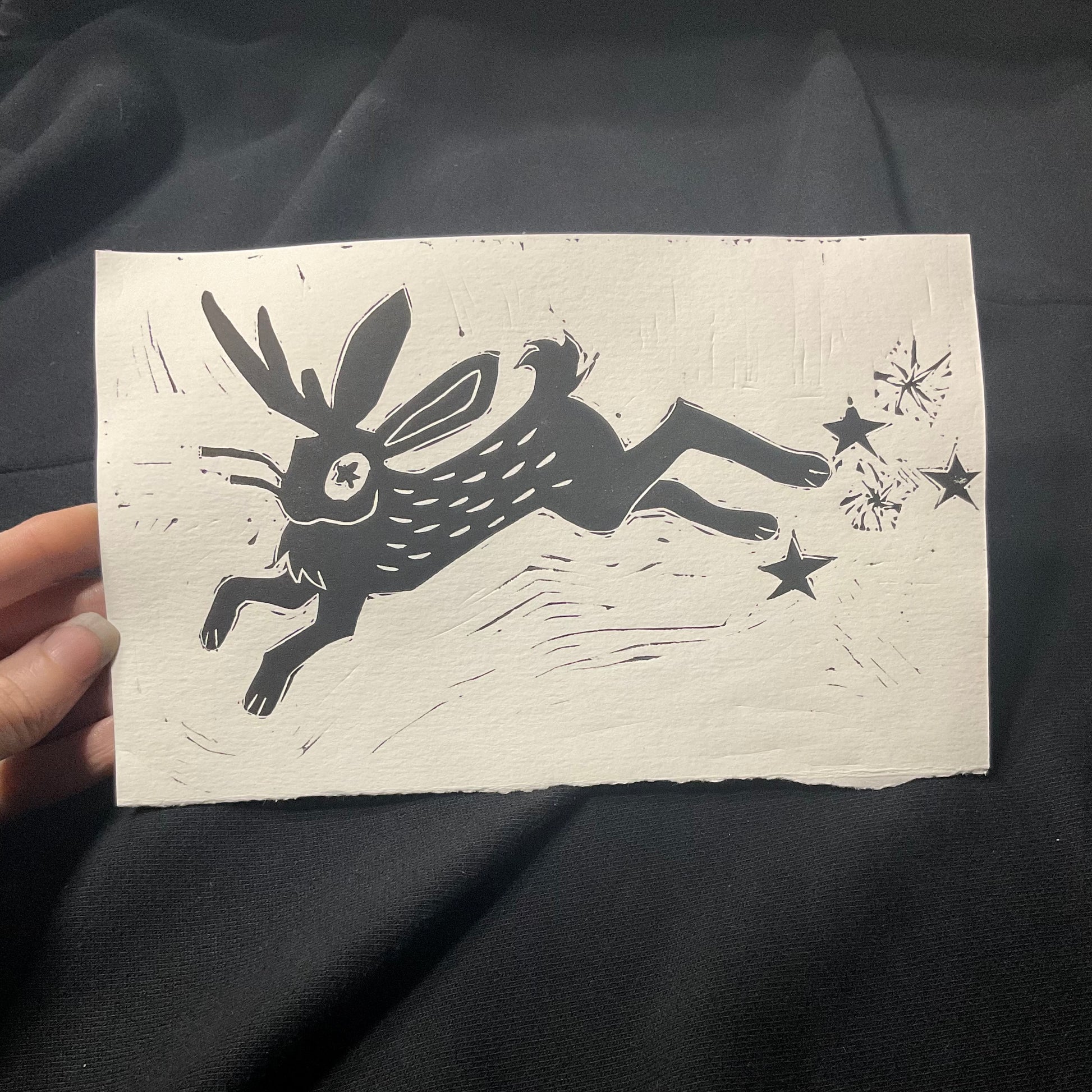 A jumping jackalope printed in black on paper.