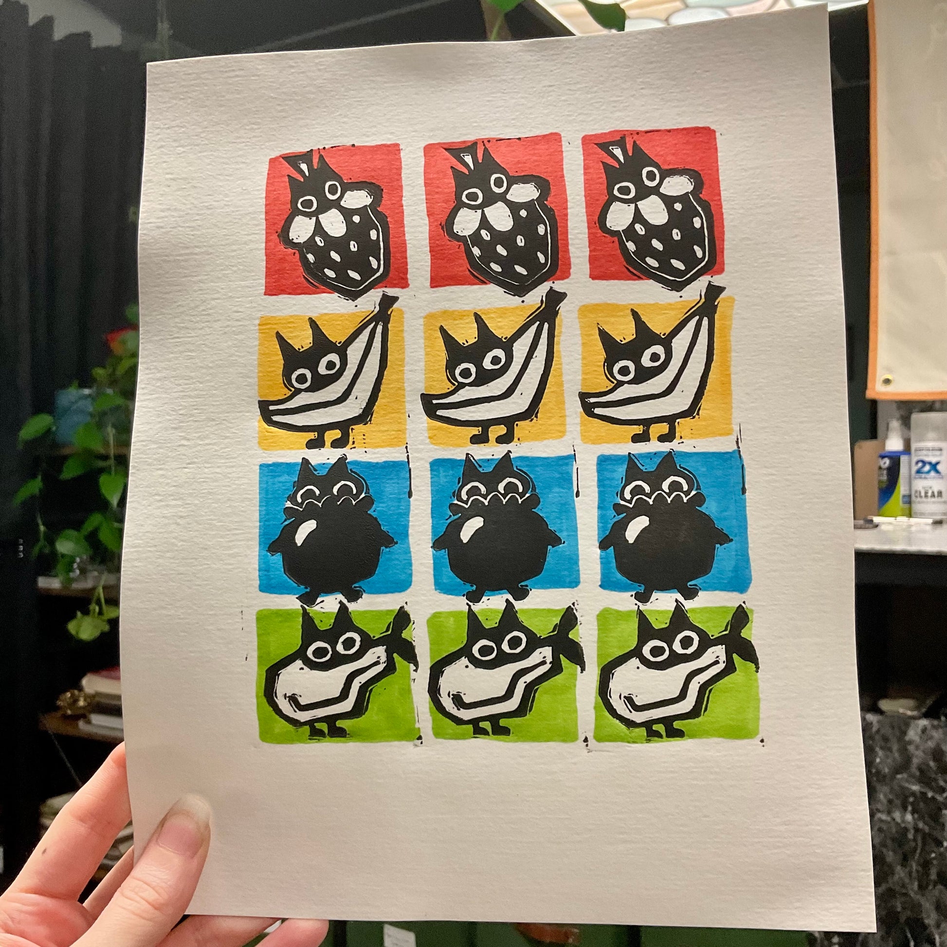 Hand holding print of cats as fruit.